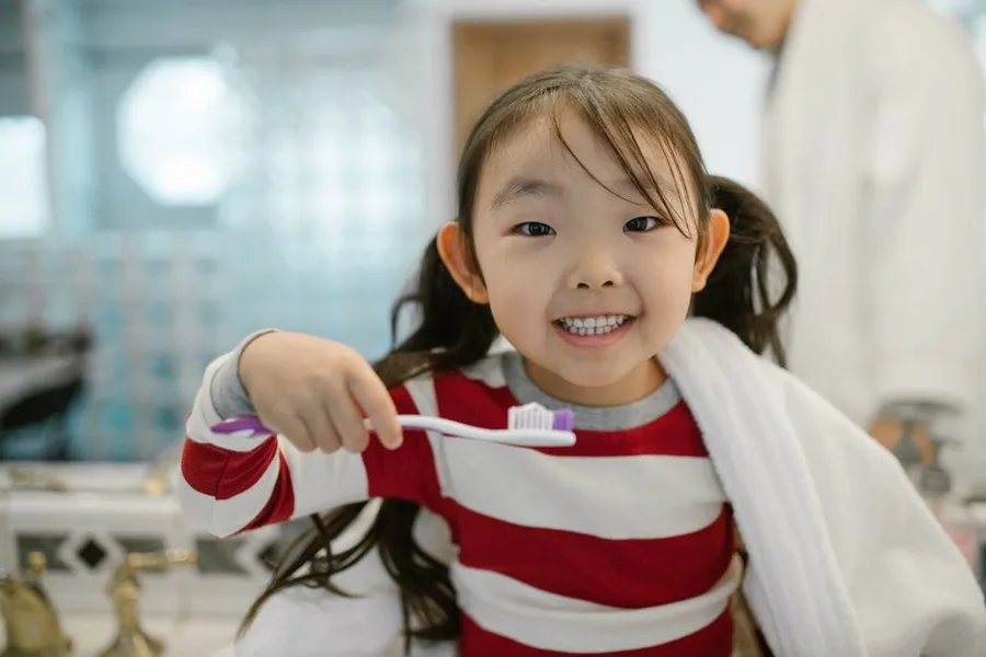 Smiling child building brushing habits before her first dental visit