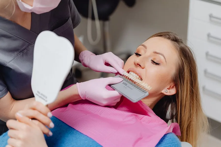 Patient checking her smile shade in a hand mirror at a Fort Myers cosmetic dentist